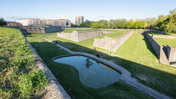 A historical fort with a moat and grassy areas, surrounded by modern buildings.