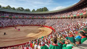 A large bullfighting arena with a crowd of spectators and performers in traditional attire.