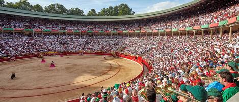 A large bullfighting arena with a crowd of spectators and performers in traditional attire.