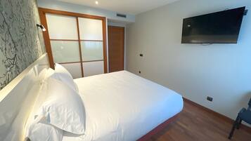 Un dormitorio con una cama, un televisor montado en la pared y una puerta corrediza.