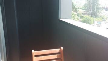 Esquina de una habitación con una silla de madera y una ventana con vistas a la carretera.