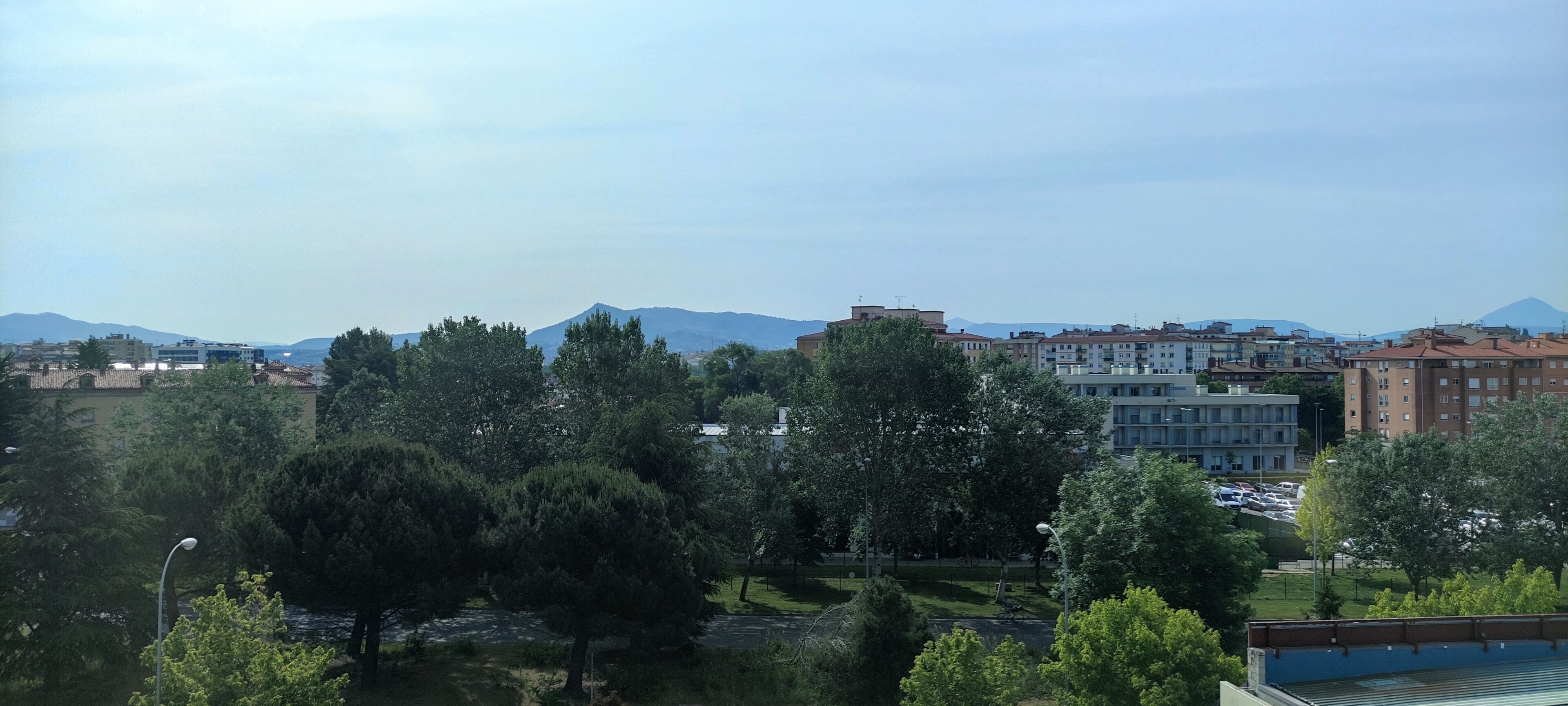 A cityscape with buildings, trees, and a mountain in the background.