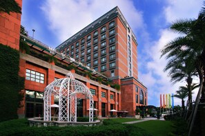A hotel with a red brick facade, a white decorative structure in front, and a clear blue sky. - Grand Victoria Hotel (Taipei)
