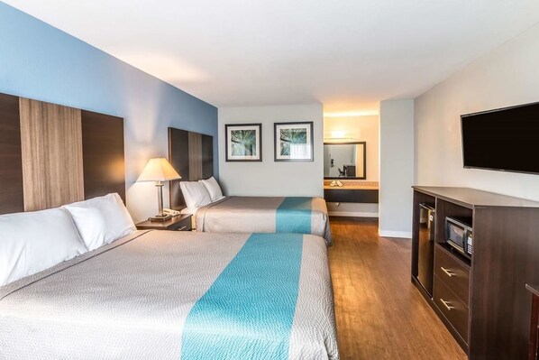 Habitación de hotel con dos camas, televisión, escritorio y microondas.