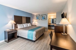 Una habitación de hotel moderna con una cama, mesitas de noche, un escritorio y un espejo.