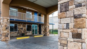 A building with a stone facade, a balcony, and a covered entrance area. - Econo Lodge Mineral Wells (Mineral Wells)