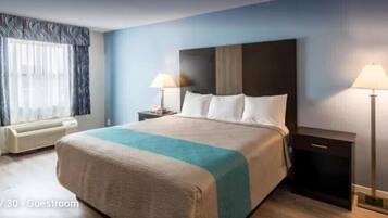 Habitación de hotel con una cama grande, dos mesitas de noche con lámparas, una ventana con cortinas y un equipo de aire acondicionado.