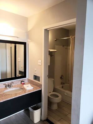 Un baño con lavamanos, espejo, inodoro y ducha.