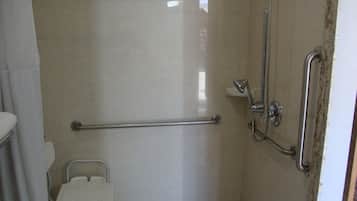 A bathroom with a shower, grab bars, and a toilet.
