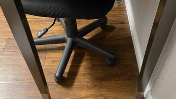 Una scrivania con sedia ergonomica in rete, una presa di corrente e una porta USB.