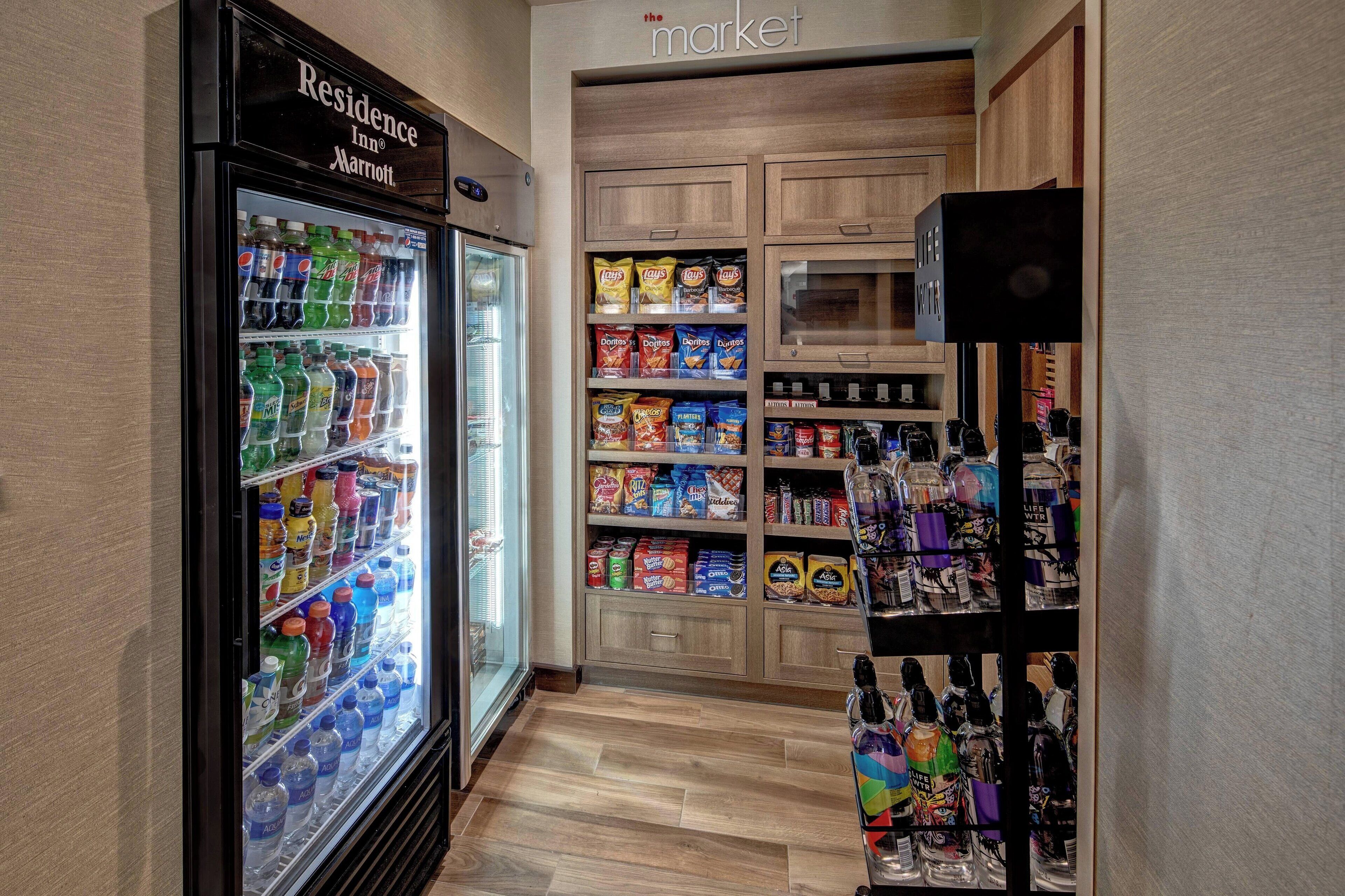 Un pasillo con un refrigerador de bebidas, estantes para aperitivos y una vitrina de licores.