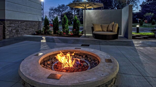 A fire pit with a metal grate and a metal plate in the center, surrounded by a stone border. - Residence Inn by Marriott Nashville at Opryland (Nashville)
