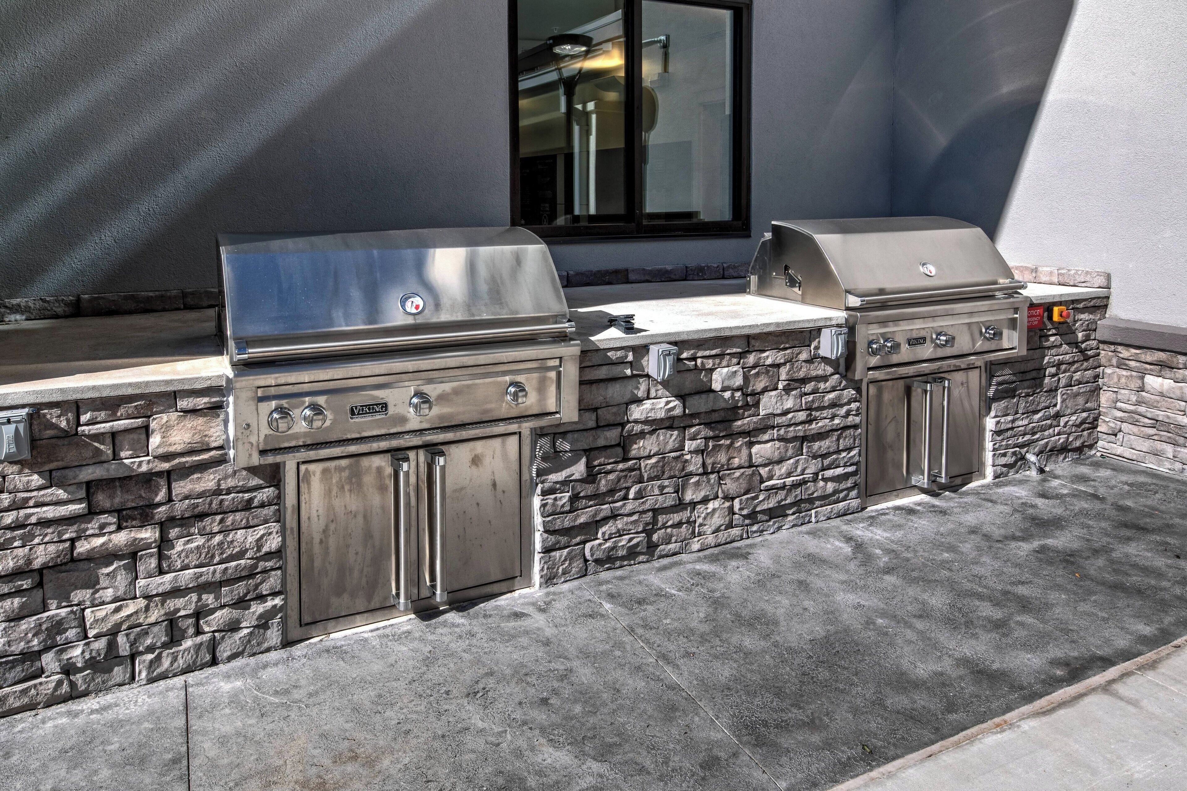 An outdoor grill area with stone walls and a window in the background.