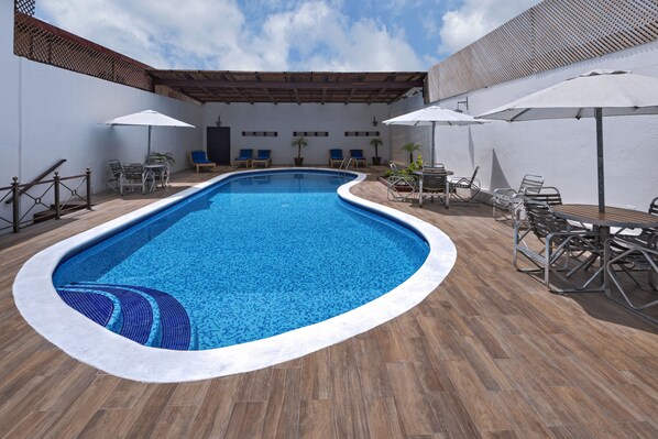 A swimming pool with a wooden deck, lounge chairs, and umbrellas. - Hotel Del Patio (Flores)