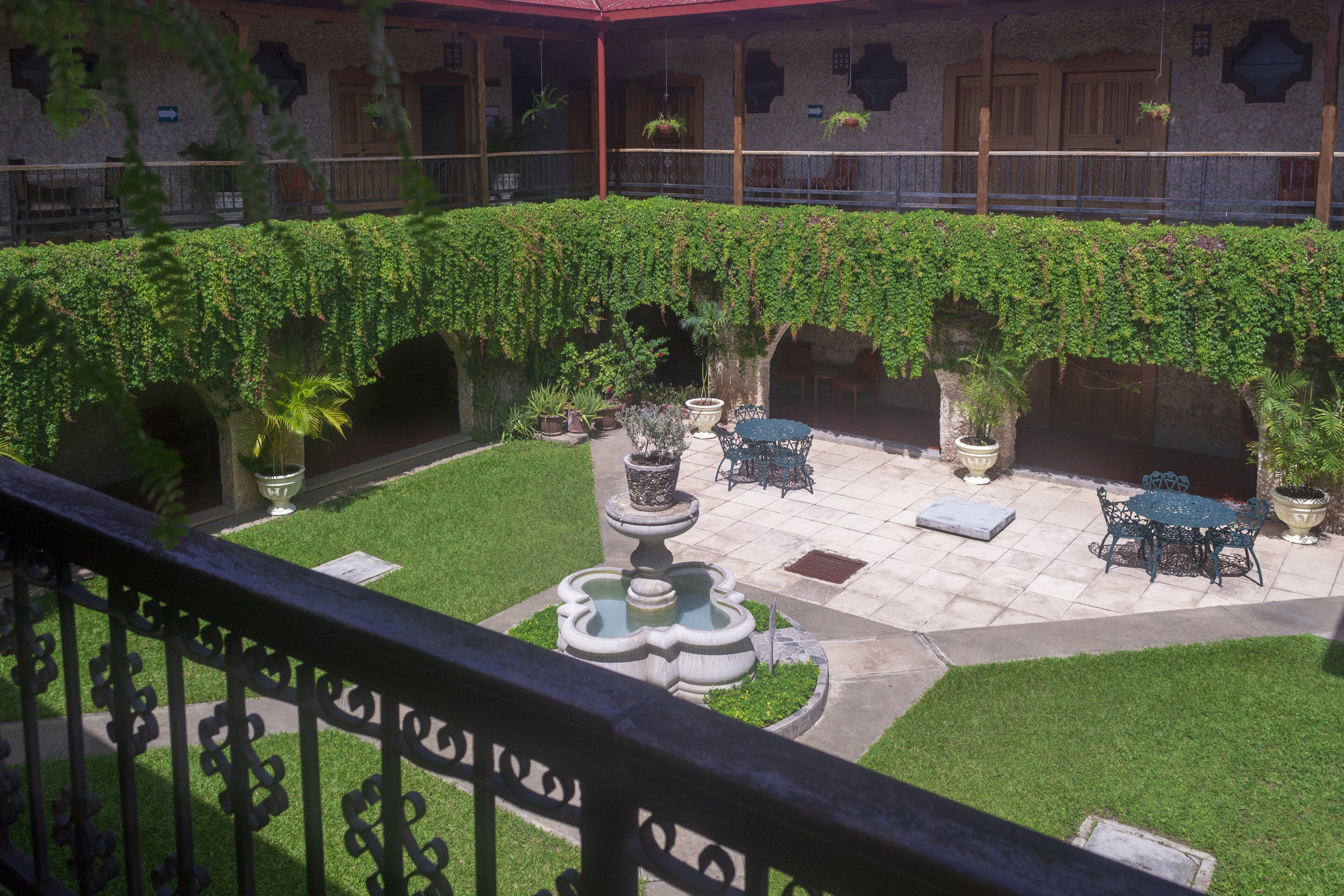 A courtyard with a fountain, potted plants, and outdoor seating.