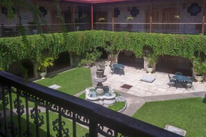 A courtyard with a fountain, potted plants, and outdoor seating. - Hotel Del Patio (Flores)
