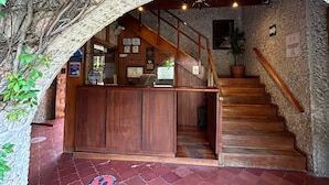 Un comptoir d’accueil en bois avec un escalier menant à un niveau supérieur.