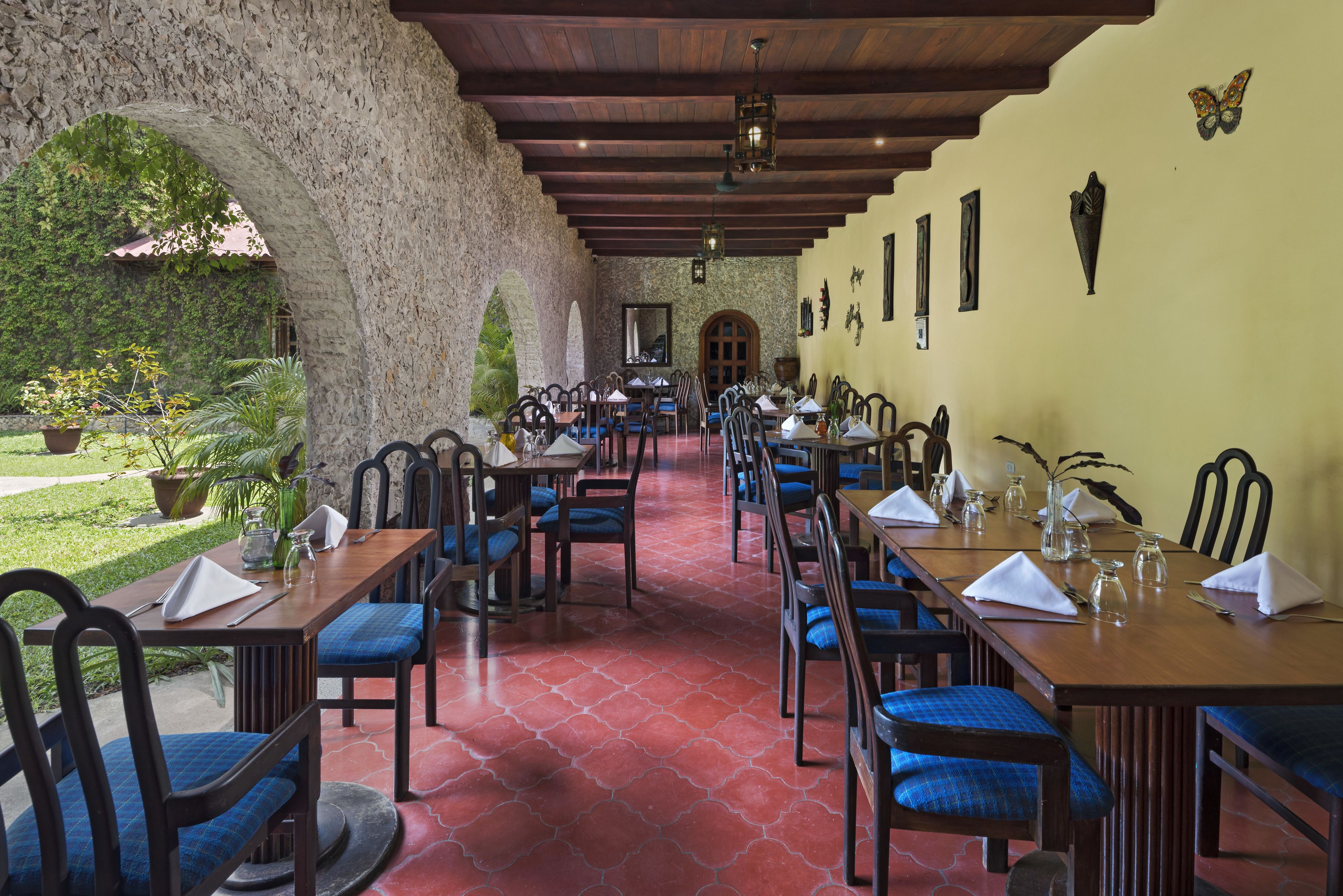 Un restaurant doté d’une grande salle à manger, d’arcs en pierre et offrant une vue sur la verdure.