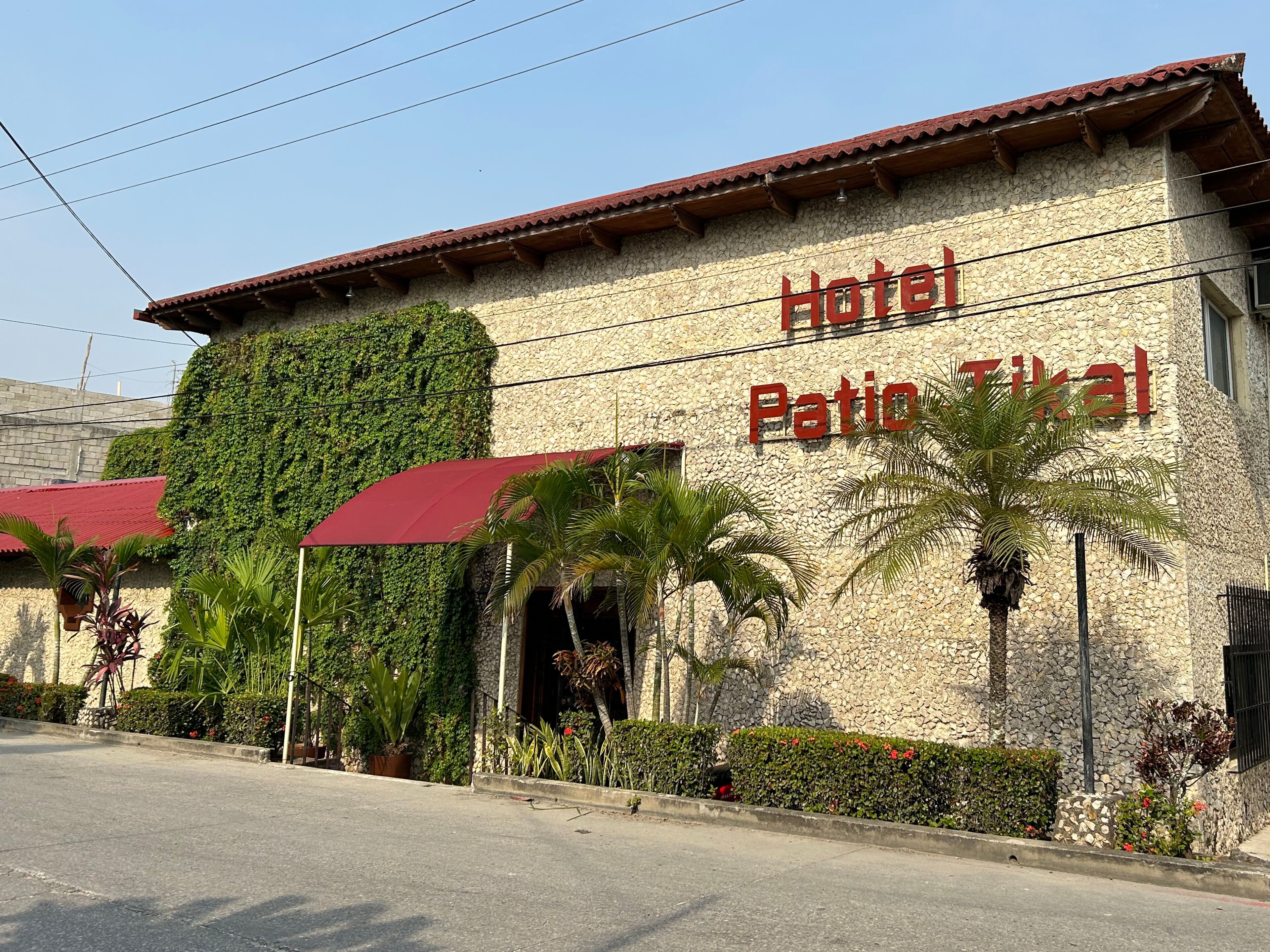 A building with a stone facade and a red roof, labeled "Hotel Patio Tropical."