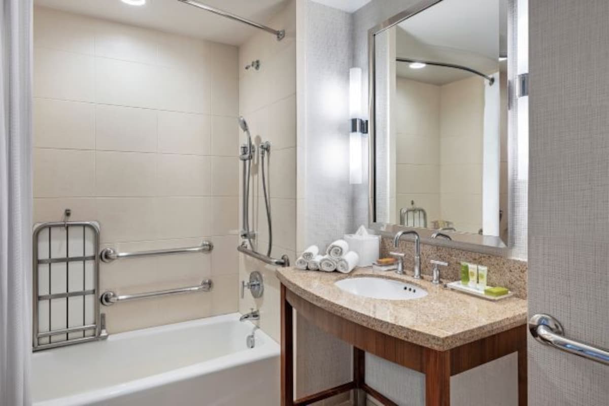 A modern bathroom with a bathtub, shower, and sink.