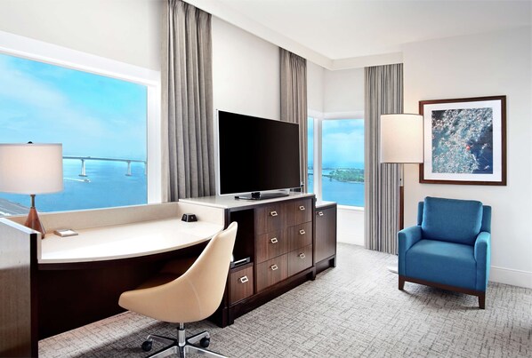 Une chambre d’hôtel équipée d’un bureau, d’une chaise, d’une télévision et offrant une vue sur un pont.