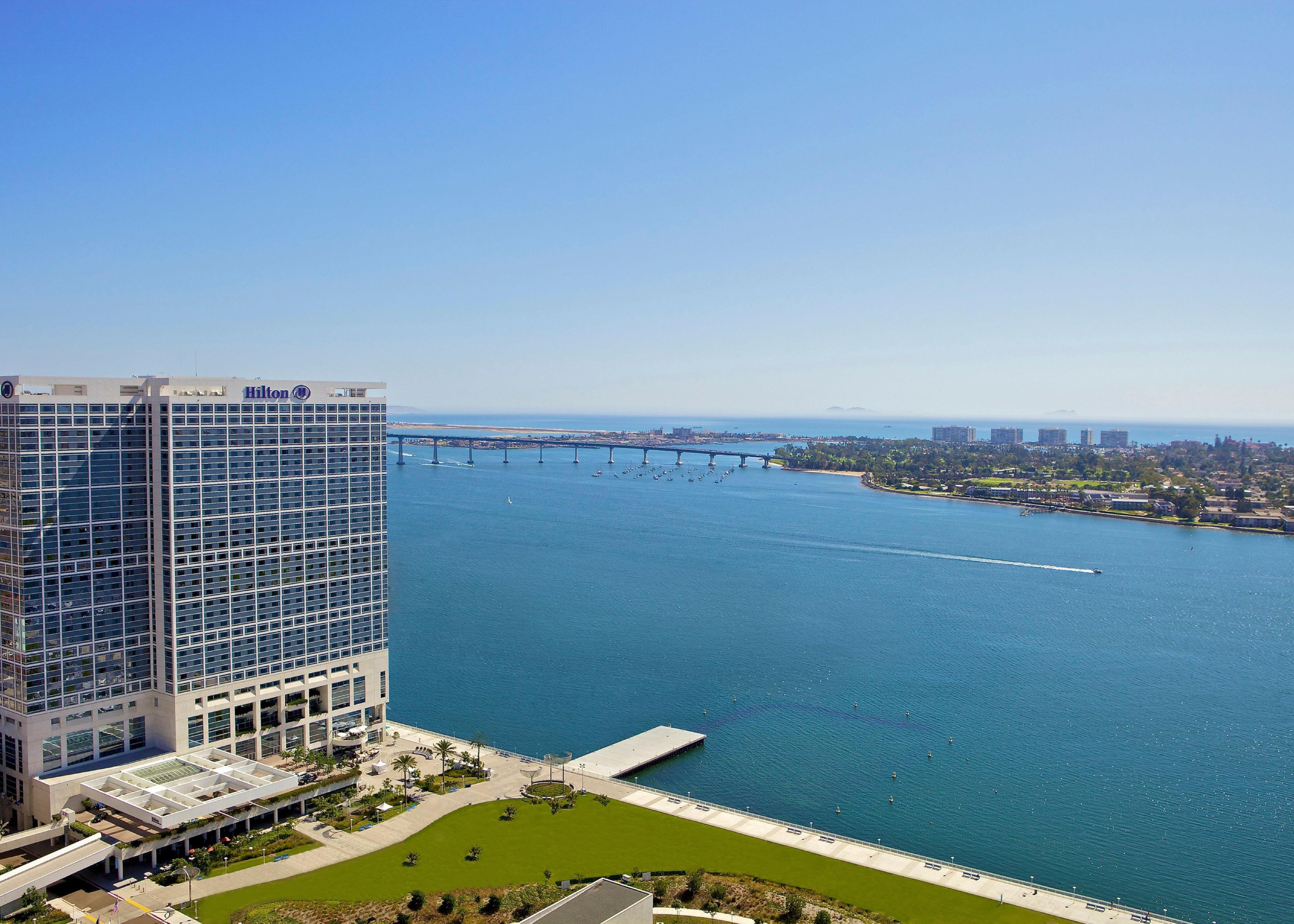 A high-rise hotel with a view of a large body of water and a bridge in the distance.