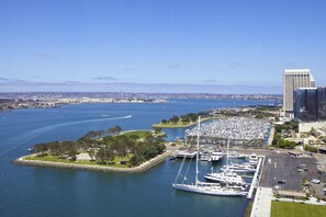 A marina with multiple yachts docked, a large building to the right, and a clear view of the water and distant cityscape. - Hilton San Diego Bayfront (San Diego)