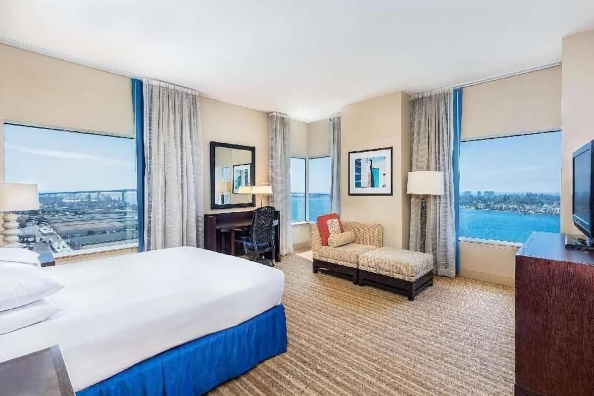 A hotel room with a large bed, a desk, a sofa, and a TV.