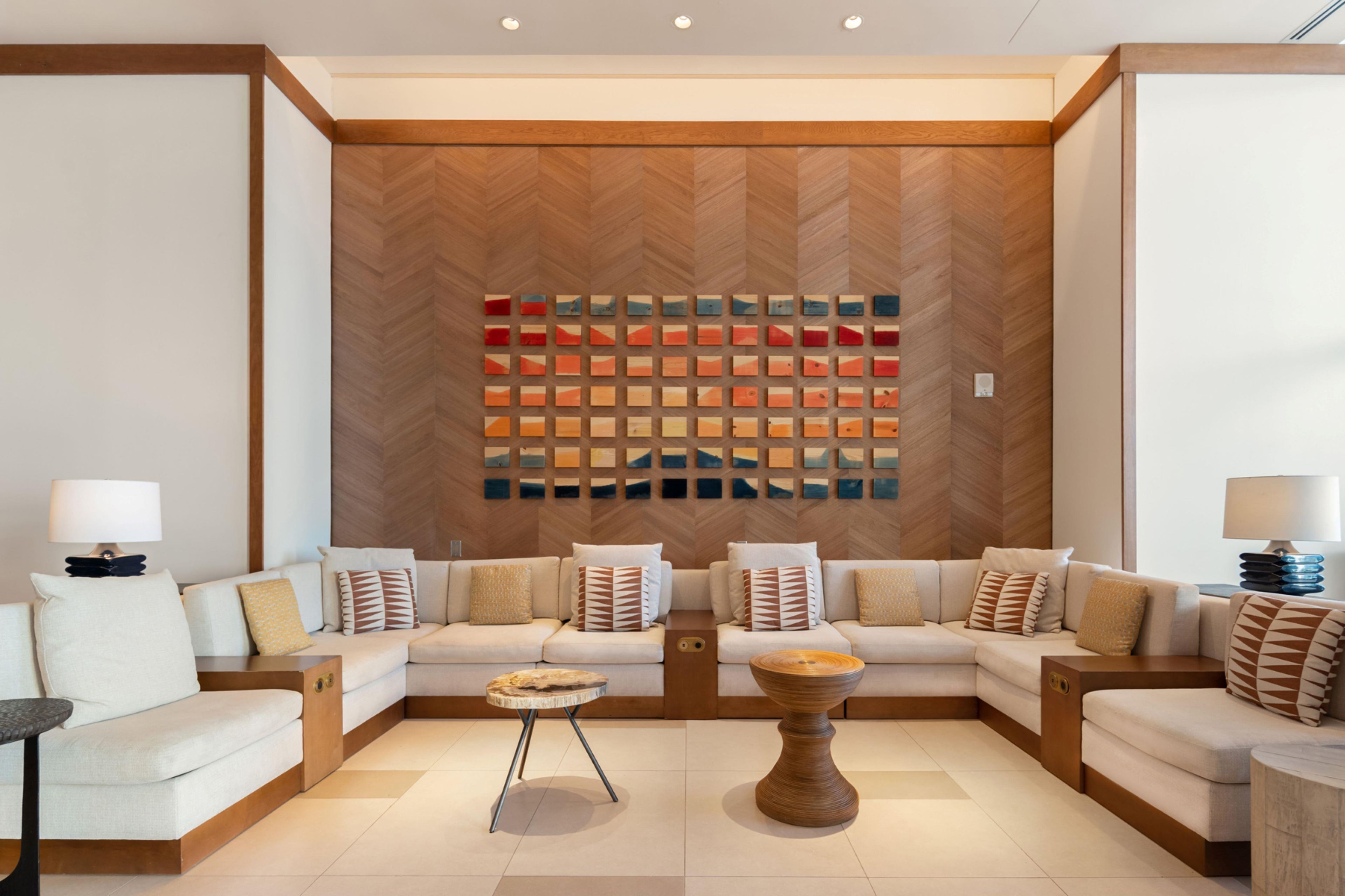 A modern living room with a herringbone-patterned wall, a sectional sofa, a coffee table, and a side table.
