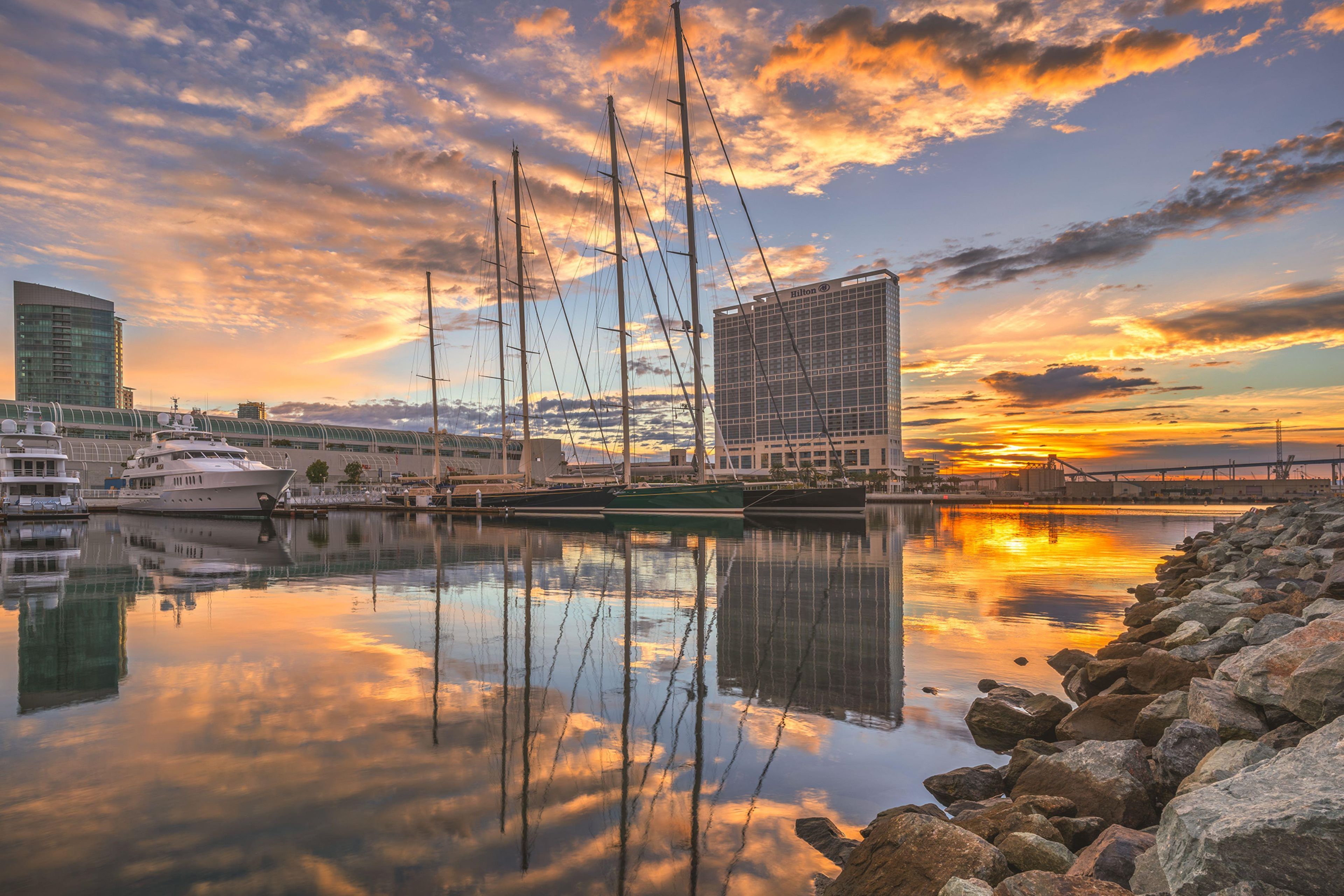 A marina with boats, a building with the Hilton logo, and a sunset.