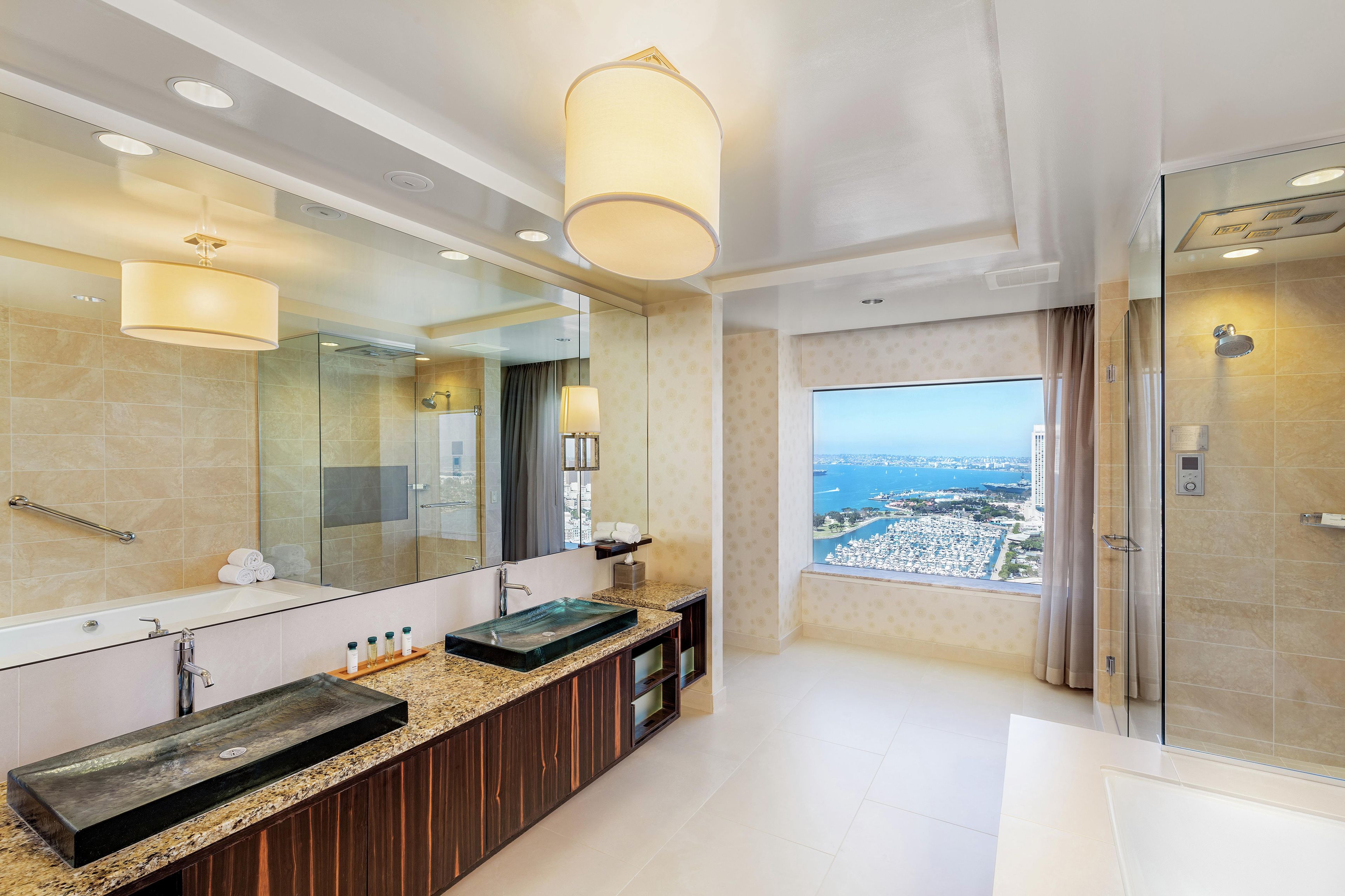 A modern bathroom with a large mirror, dual sinks, and a shower.