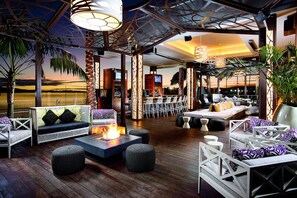 An outdoor lounge area with seating, a fire feature, and a view of the sunset. - Hilton San Diego Bayfront (San Diego)