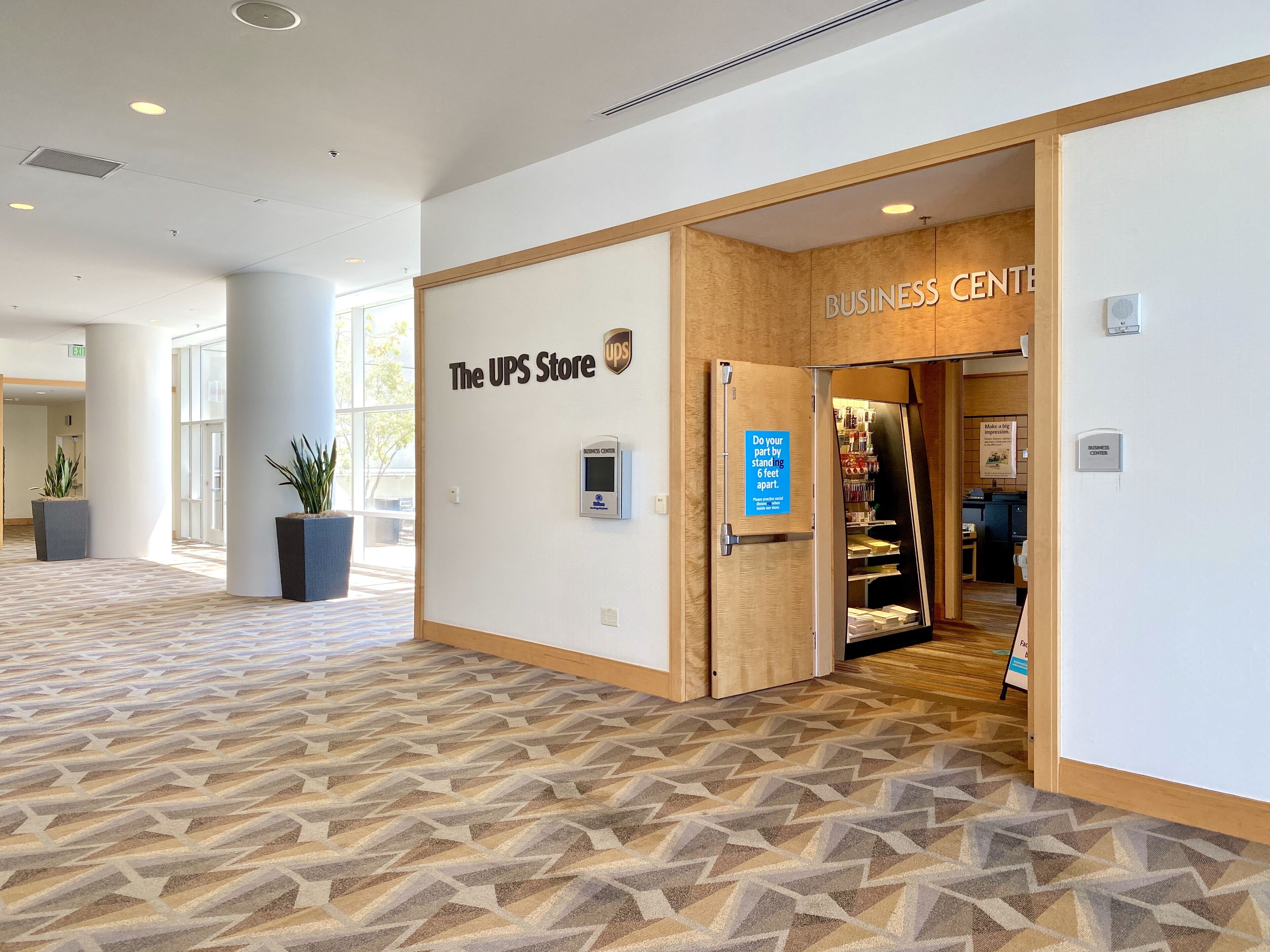 A UPS store with a business center, a sign indicating social distancing, and a patterned floor.