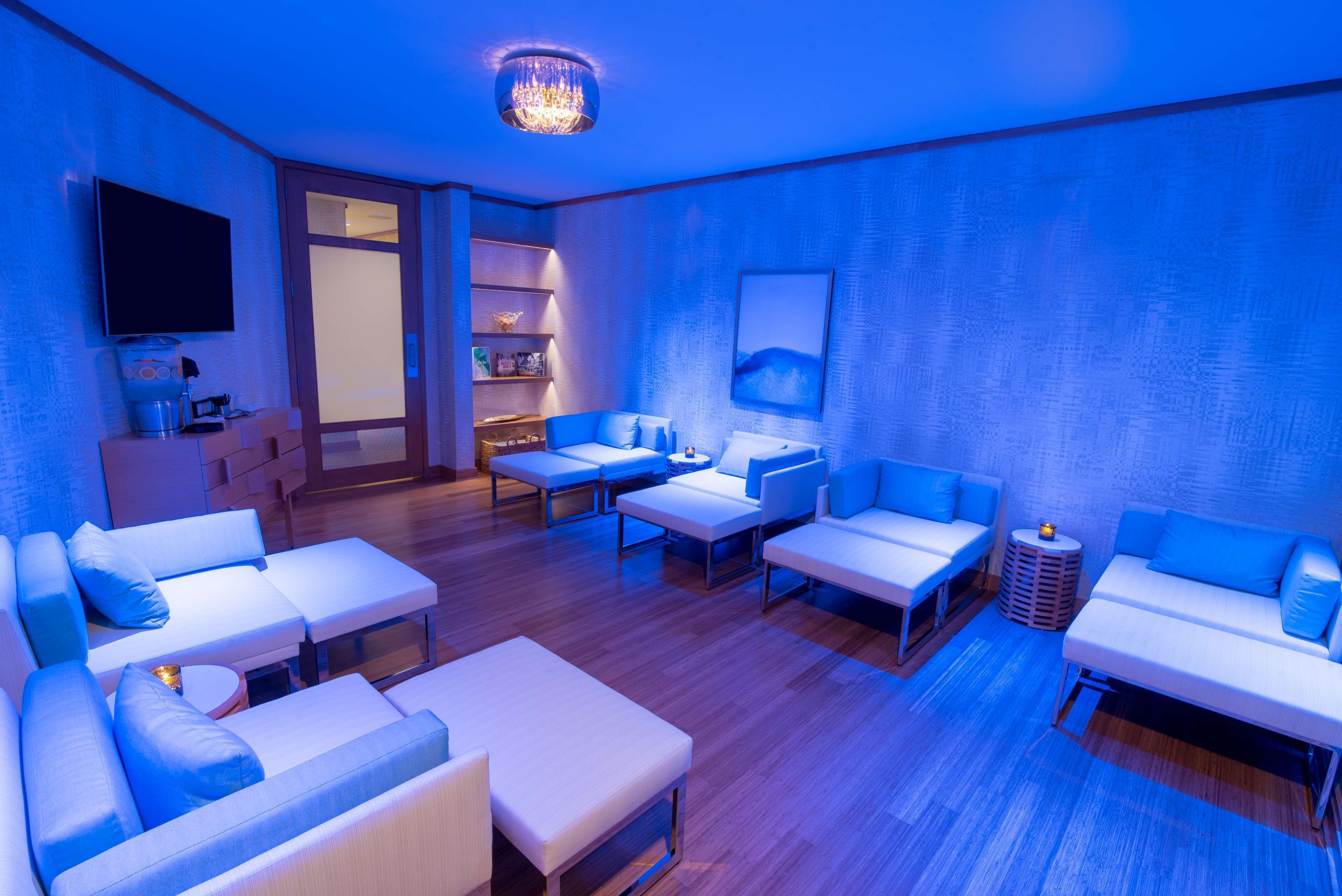 Een moderne woonkamer met een blauwe sfeer, met banken, een salontafel en een televisie.