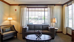 A hotel room with a sofa, a round table, and two lamps.