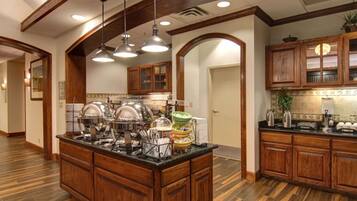 Una cocina con armarios de madera, una isla central con fregadero e iluminación colgante.