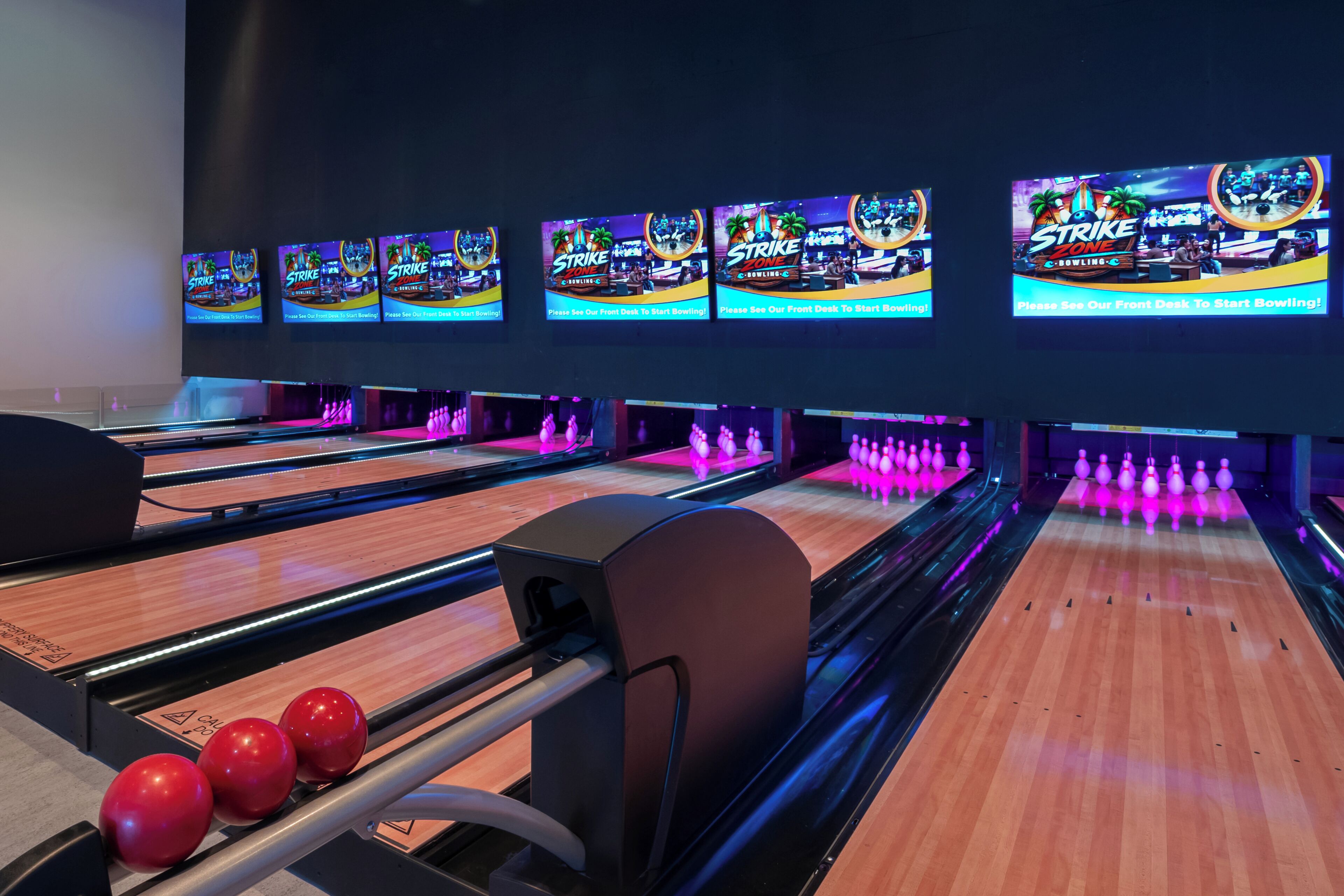 Un bowling doté de plusieurs pistes, d’un comptoir d’accueil et de plusieurs boules de bowling.