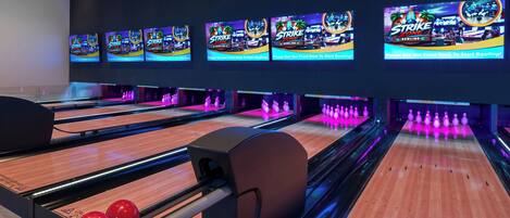 Un bowling doté de plusieurs pistes, d’un comptoir d’accueil et de plusieurs boules de bowling.