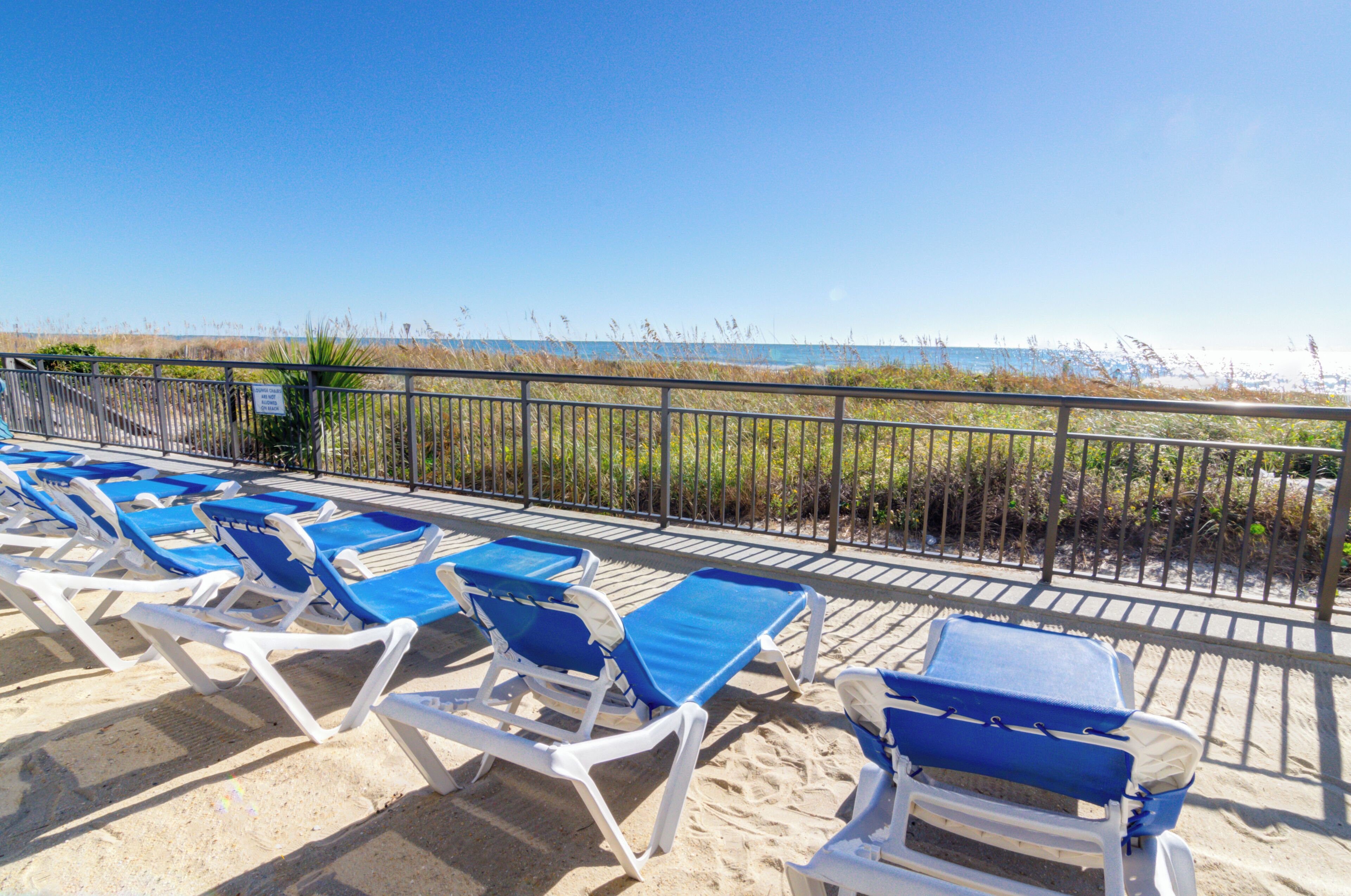 A beachside area with rows of blue and white sun loungers facing the ocean.