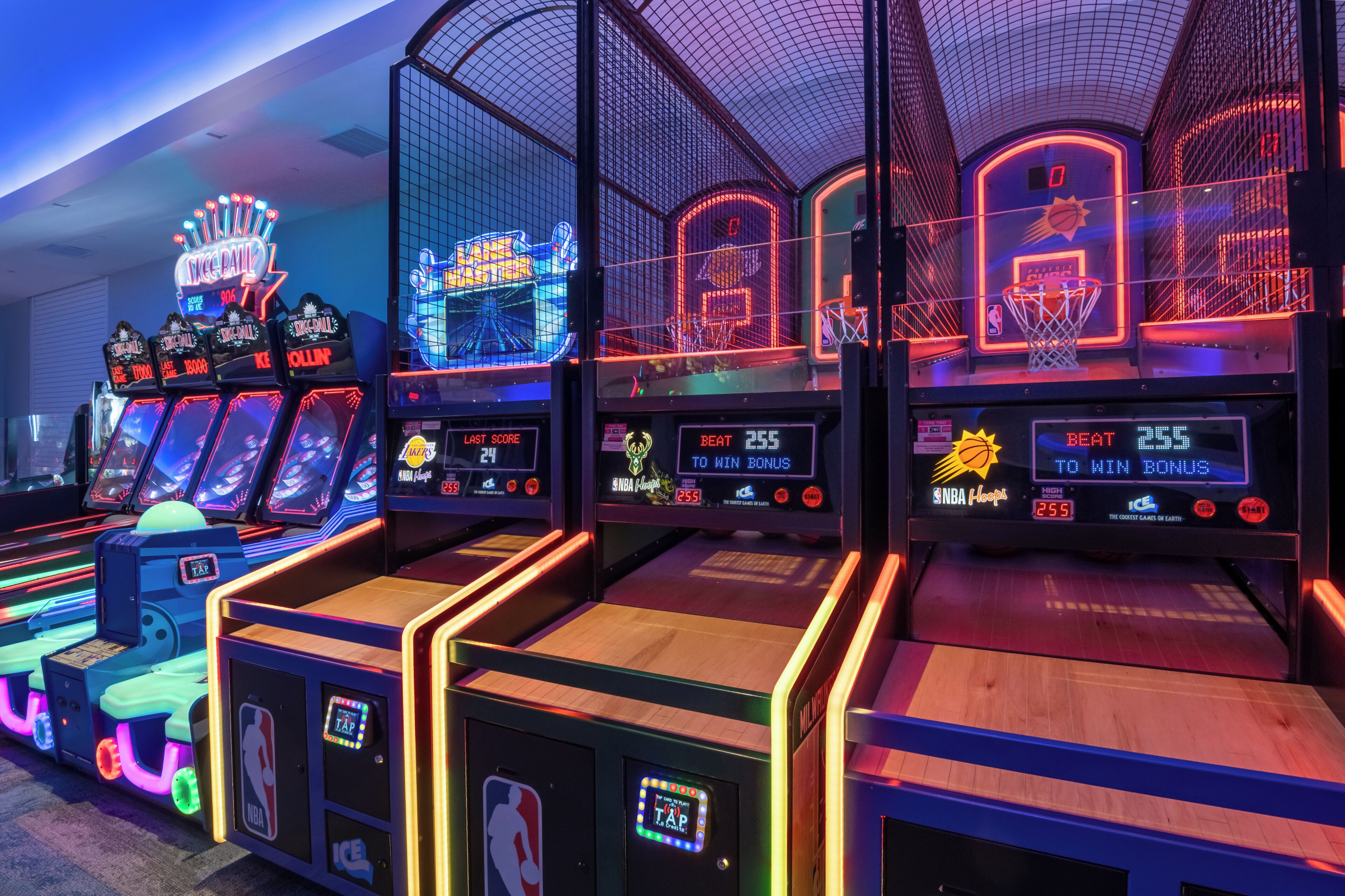 A row of arcade basketball machines with digital score displays.