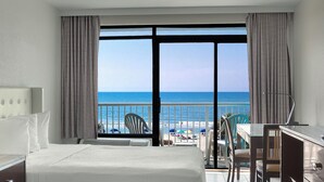 A hotel room with a large window offering a view of the beach and ocean. - Captain's Quarters Resort (Myrtle Beach)