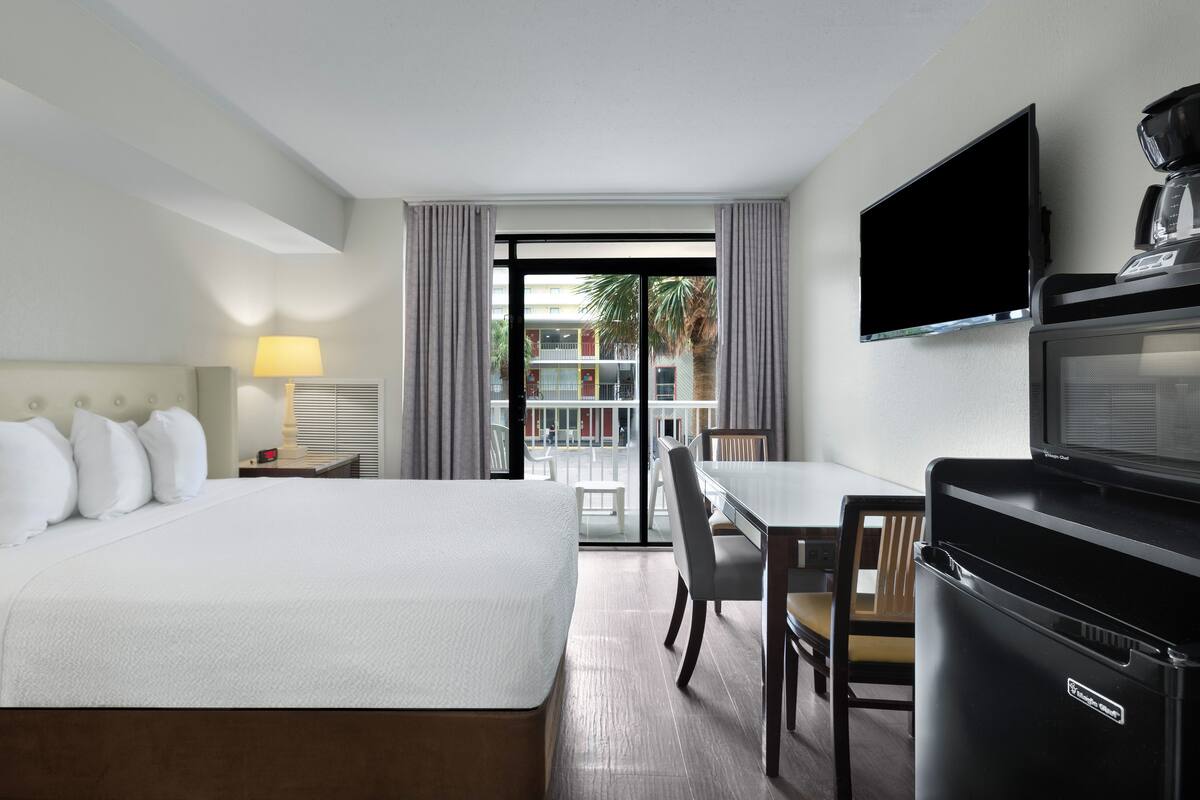A hotel room with a bed, a desk, a TV, and a microwave.