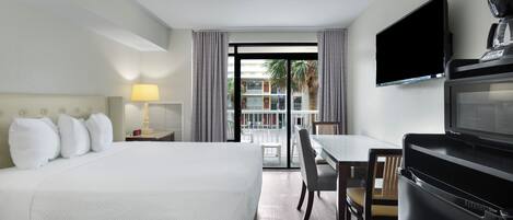 A hotel room with a bed, a desk, a TV, and a microwave.