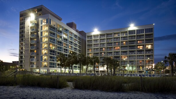 A multi-story hotel with balconies, large windows, and a beach view. - Captain's Quarters Resort (Myrtle Beach)