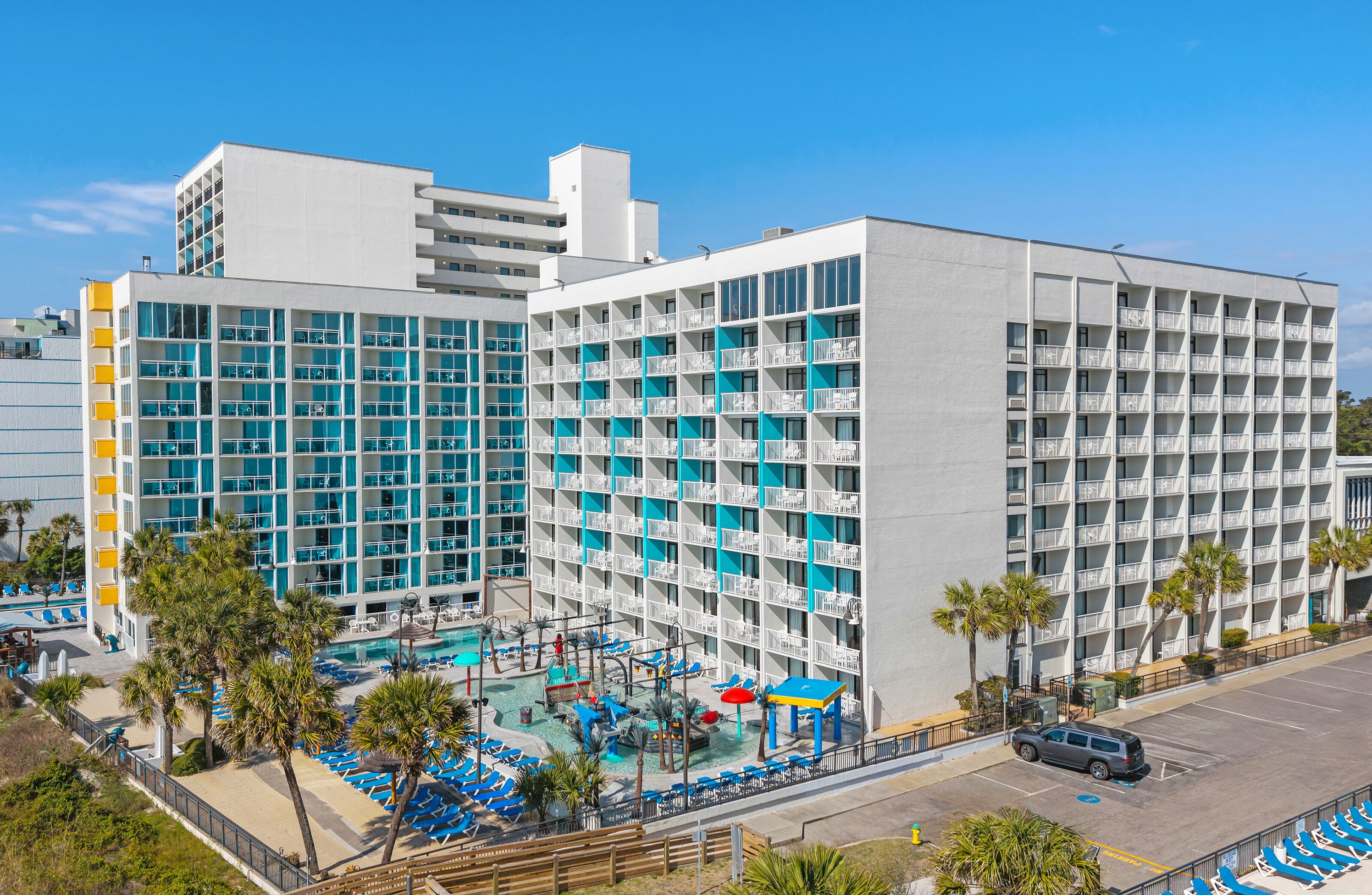 Un hôtel doté de nombreux balcons, d’une piscine et d’un parking.