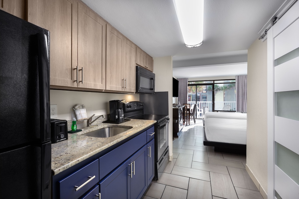 A modern kitchen with wooden cabinets, a black refrigerator, a microwave, and a coffee maker.