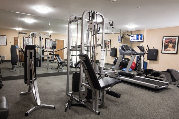 A gym with various exercise equipment, a television, and a mirror.