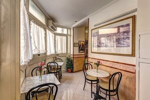 A dining area with tables and chairs, a potted plant, and a framed artwork on the wall. - Hotel Giuliana (Rome)