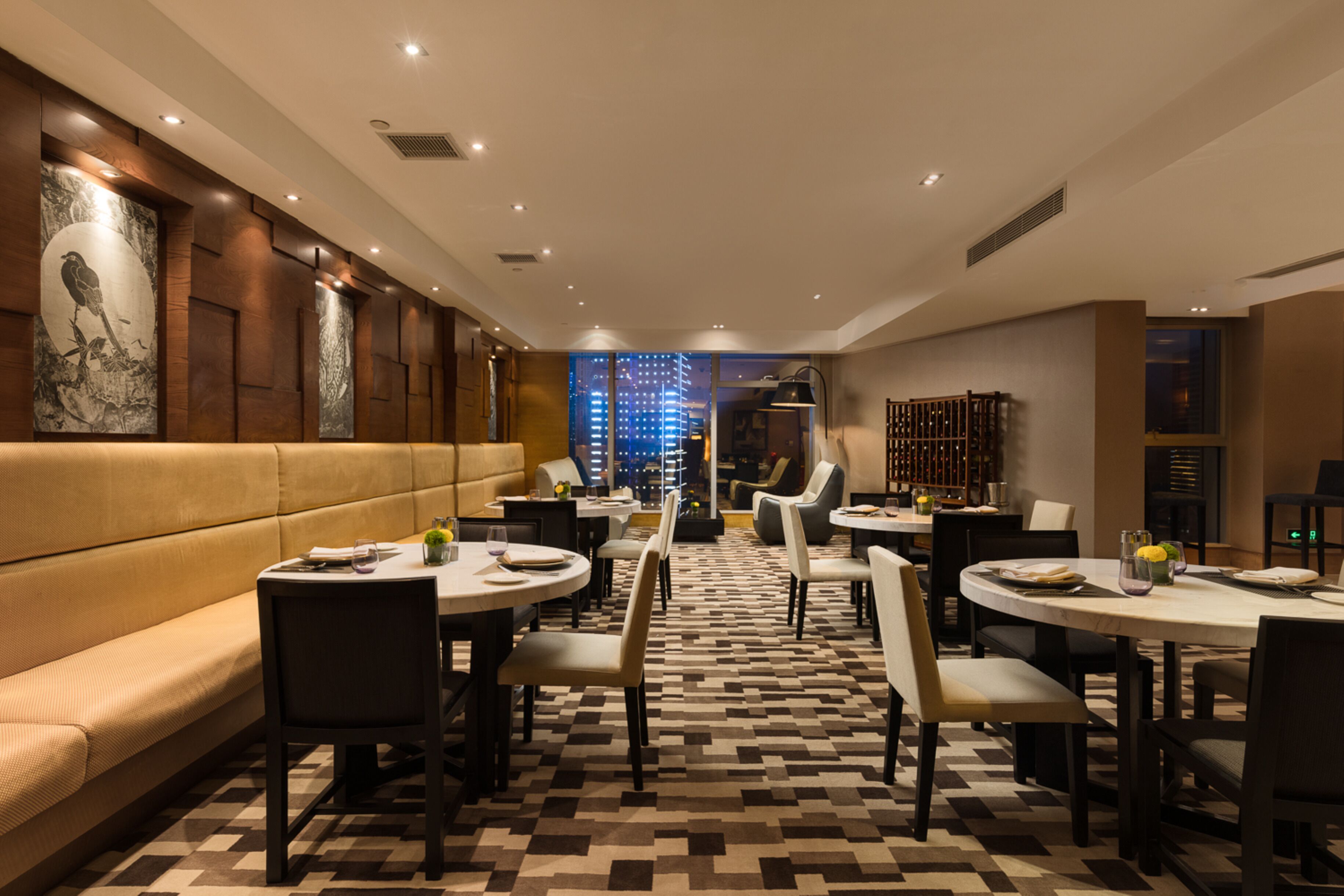 A modern dining area with a checkered floor, round tables, and cushioned seating.