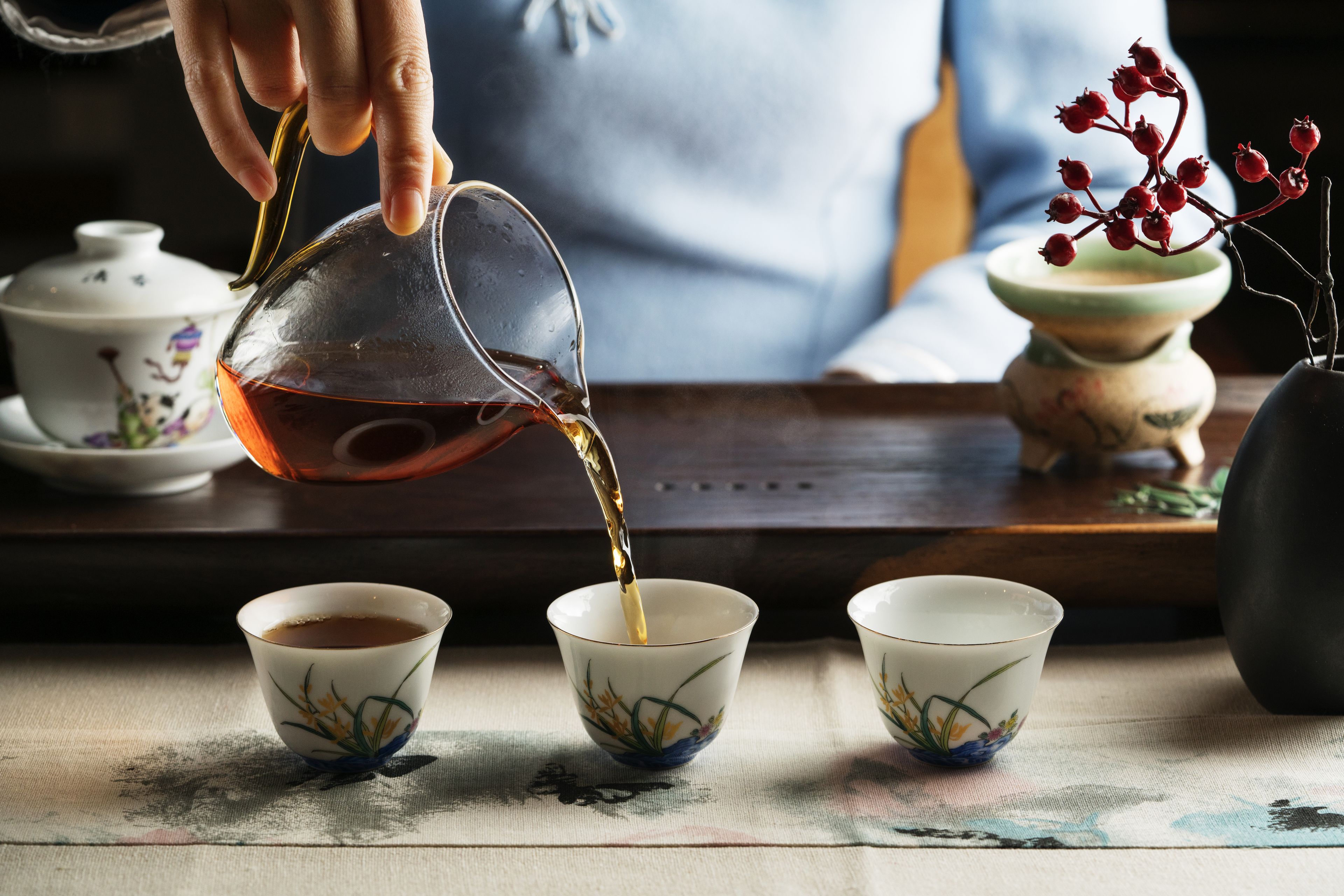 A hand pouring tea into a cup.